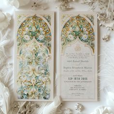 an ornate wedding card with white flowers and feathers on the side, surrounded by other decorations