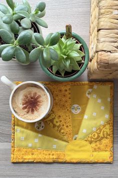 a cup of coffee sitting on top of a table next to a potted plant