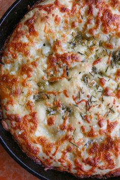 a pizza with cheese and herbs on it sitting in a pan, ready to be eaten