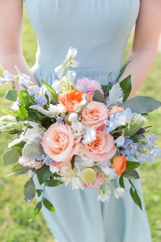 a bridesmaid holding a bouquet of flowers in her hands and wearing a blue dress