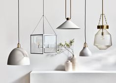 an assortment of hanging lights in various shades of white, gold and grey on a wall