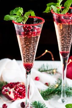 two champagne flutes filled with cranberry and mint garnish on a table