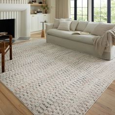 a living room filled with furniture and a large rug on top of a hard wood floor