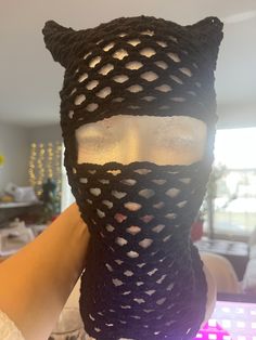 a person wearing a black knitted cat mask with holes on it's face