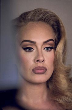 a woman with long blonde hair and blue eyeshadow is looking at the camera