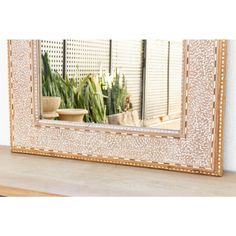 a mirror sitting on top of a wooden table next to a potted plant in front of it