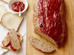 a loaf of bread sitting on top of a cutting board next to slices of bread covered in ketchup