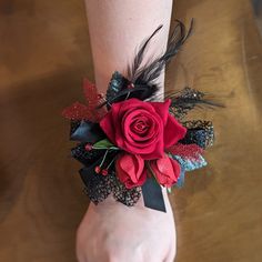 a woman's wrist with a red rose and feathers on it