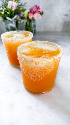 two glasses filled with orange juice on top of a table