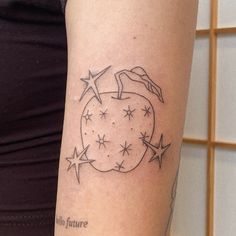 a woman's arm with an apple and stars tattoo on the left side of her arm