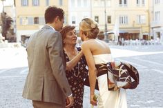 two women and a man are standing on the street talking to each other while holding hands