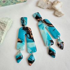 three pieces of jewelry sitting on top of a table next to some rocks and stones