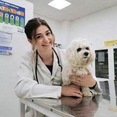 a woman in white lab coat holding a dog