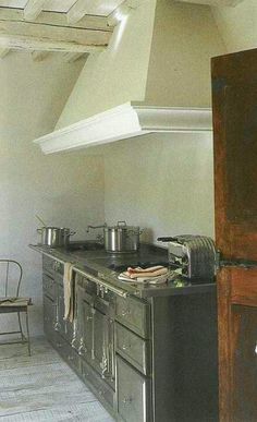 an old fashioned kitchen with pots and pans on the stove top, next to a chair