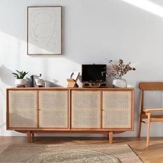 a living room with white walls and wooden furniture, including a television on top of a wicker cabinet