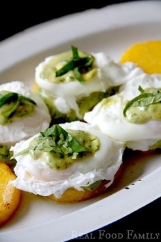 small appetizers are arranged on a plate with oranges and green garnish