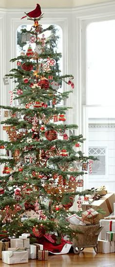 a small christmas tree with presents under it in front of a window and a bird on top