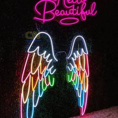 neon angel wings on display in front of a sign with the words real beautiful written above it