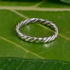 a silver ring sitting on top of a green leaf