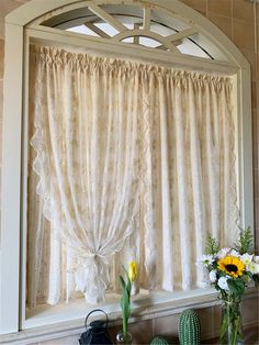 a window with curtains and vases on the ledge in front of it, next to a potted plant