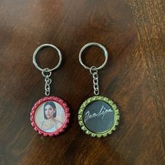 two personalized bottle caps are sitting on a table with a keychain attached to them