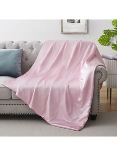 a couch with a pink blanket on top of it next to a potted plant