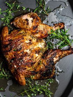 two pieces of chicken on a plate with herbs