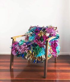 a chair made out of tinsel is sitting on a hard wood floor in front of a white wall