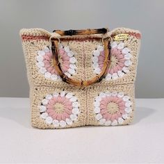 a crocheted bag with flowers on the front and handles is sitting on a table