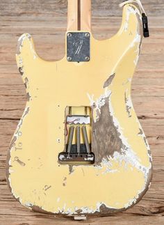 an old yellow electric guitar sitting on top of a wooden floor