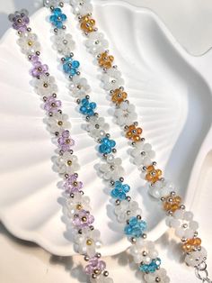 three strands of multicolored glass beads on a white seashell with a silver chain