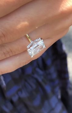 a woman's hand holding an engagement ring with a large diamond in the middle