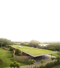 an aerial view of a green roof in the middle of a grassy area with trees and bushes