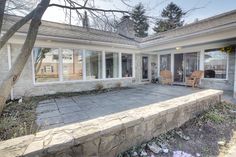 a house with large windows and stone steps leading up to the front door that leads into the back yard