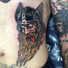 a close up of a man's chest with tattoos on it and an image of a viking