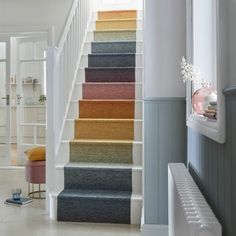 a staircase with carpeted steps leading up to the first floor and another room in the background