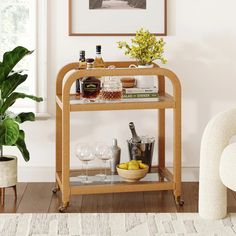 a wicker bar cart with wine glasses and bottles on it in a living room