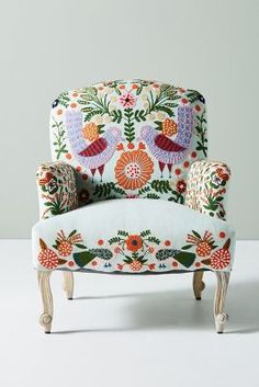 an upholstered chair with birds and flowers on it