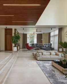 a living room filled with lots of furniture next to a tall ceiling mounted flat screen tv