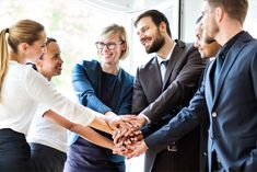 a group of business people stacking their hands together