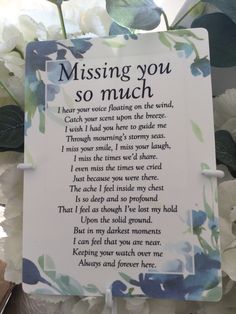 a poem written on a plaque surrounded by white and blue flowers with the words missing you so much