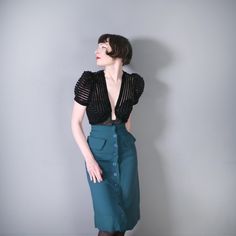 70s handmade dark teal a-line high waist skirt with button fastened front. Wide fitted waistband. Decorative pocket flaps on the hip. Fabric feels like a soft rayon. Cute a-line silhouette with a 70s does Art Deco / 40s vibe to it. Approx knee length. Unlined. SIZE The skirt is not labeled with a size but fits approx like an XS. For your best fit please refer to the measurements. Fit on model: as shown Waist: 24" Hip: 36" Length: 27" Sweep: (There is a 2.5" hem on this) CONDITION Good condition. 1950s Style Fitted Pleated Skirt, Fitted Pleated Skirt In 1950s Style, Fitted Pleated Skirt In Vintage Style, Retro Fitted Skirt With Buttons, Fitted Green Skirt With Buttons, Retro Fitted Skirt With Button Closure, Retro Knee-length Party Bottoms, Fitted Green Skirt With Button Closure, Vintage Fitted Skirt With Buttons