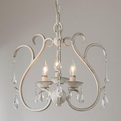 a white chandelier with three lights hanging from it's sides and two candles on each side