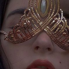 a woman is wearing a gold mask with jewels on it's face and her eyes are closed