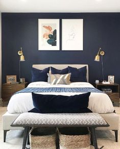 a bedroom with blue walls, white bedding and two framed pictures on the wall