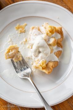 a white plate topped with a pastry covered in icing next to a knife and fork