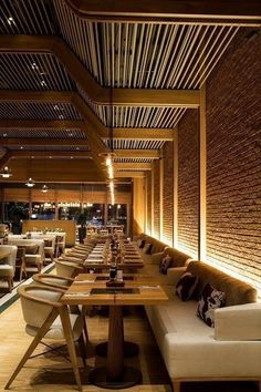 a restaurant with wooden tables and white couches in the center, along with brick walls