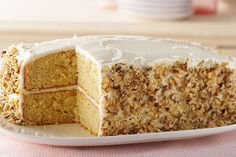 a white plate topped with a cake covered in frosting and nuts on top of a pink table cloth