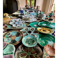 a table topped with lots of plates covered in different colors and designs on top of each other