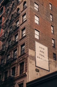 a tall brick building with a sign on the side that says how are you really?